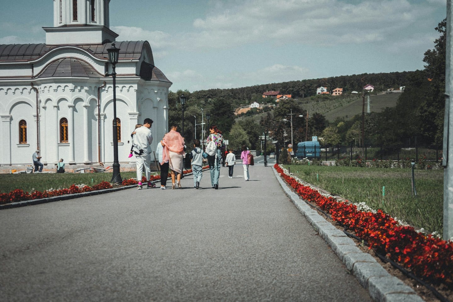 Persone camminano lungo un sentiero verso una grande chiesa bianca.